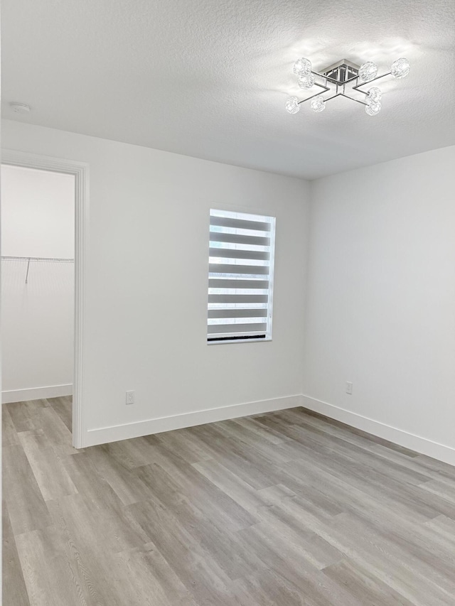 spare room with a textured ceiling and light wood-type flooring