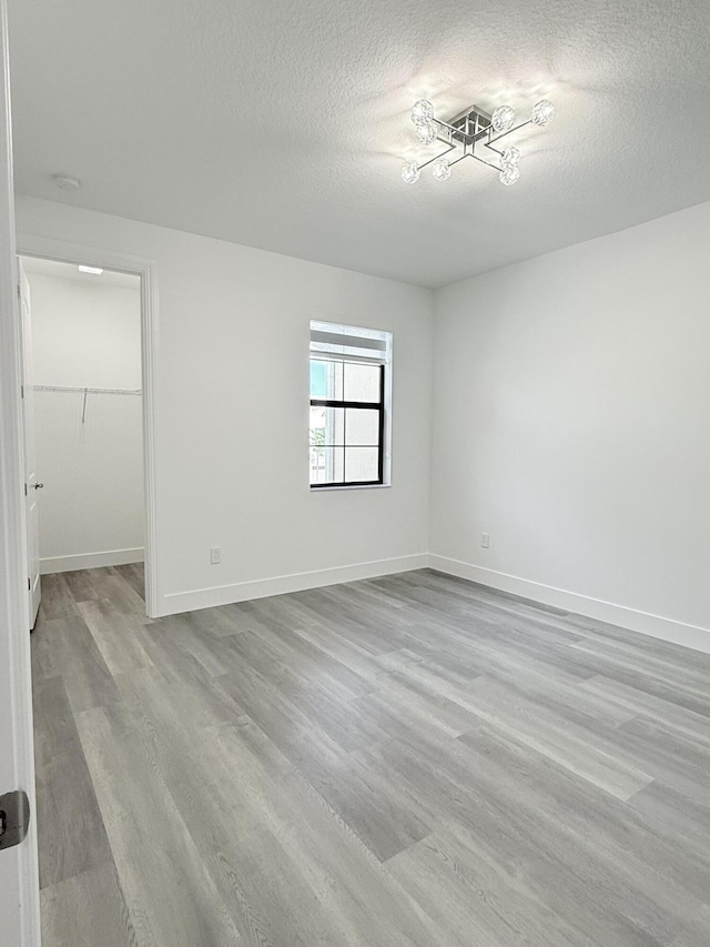 empty room featuring a textured ceiling and light hardwood / wood-style flooring