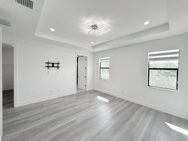 unfurnished room with a raised ceiling and light hardwood / wood-style floors