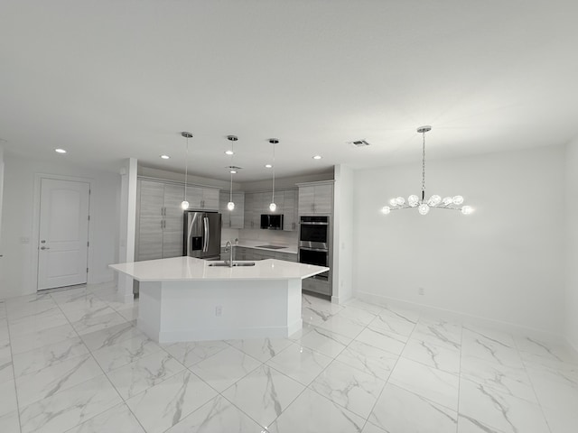 kitchen featuring pendant lighting, sink, stainless steel appliances, and an island with sink