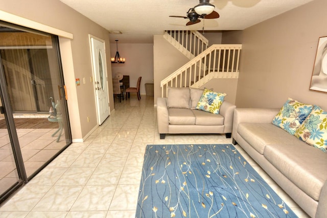 tiled living room with ceiling fan with notable chandelier and a textured ceiling