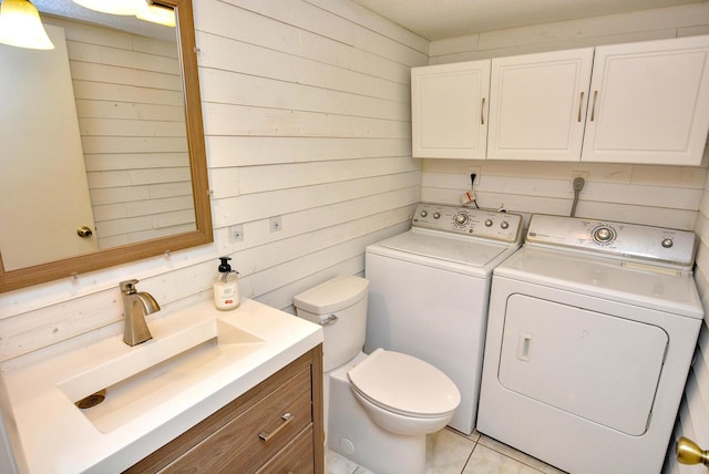 bathroom with vanity, wood walls, tile patterned floors, washer and dryer, and toilet