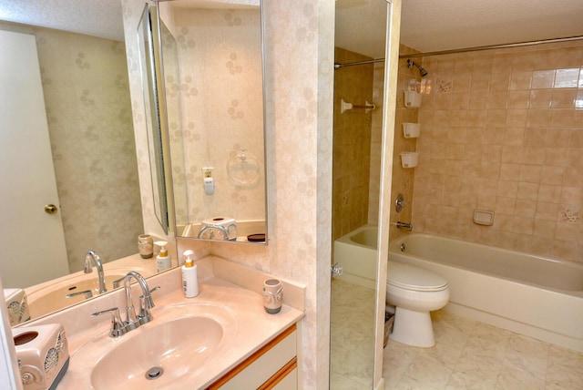 full bathroom with a textured ceiling, vanity, toilet, and tiled shower / bath