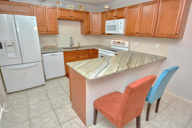 kitchen with kitchen peninsula, light stone countertops, sink, and white appliances