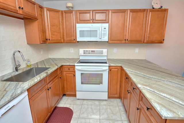 kitchen with light stone countertops, backsplash, white appliances, sink, and light tile patterned floors