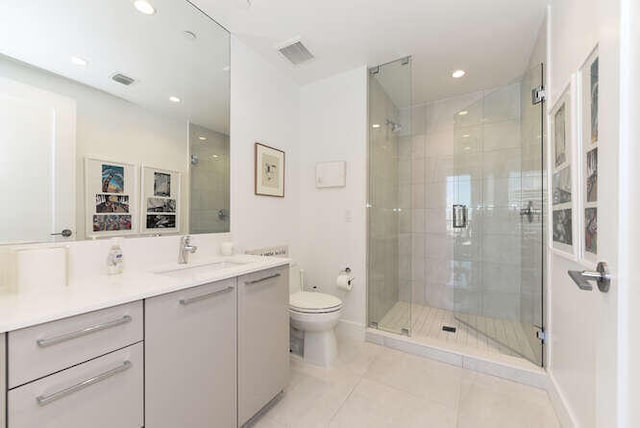 bathroom with tile patterned flooring, vanity, a shower with door, and toilet