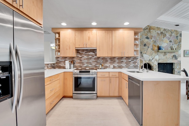 kitchen featuring sink, stainless steel appliances, tasteful backsplash, kitchen peninsula, and light brown cabinetry