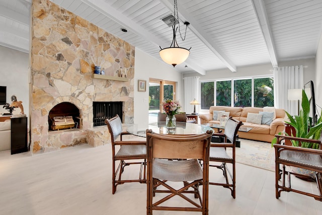 dining area featuring a fireplace and vaulted ceiling with beams