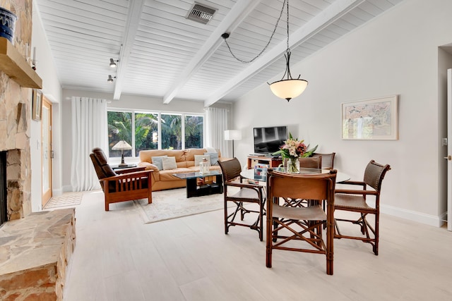 dining space featuring wood ceiling, a stone fireplace, light hardwood / wood-style flooring, and lofted ceiling with beams