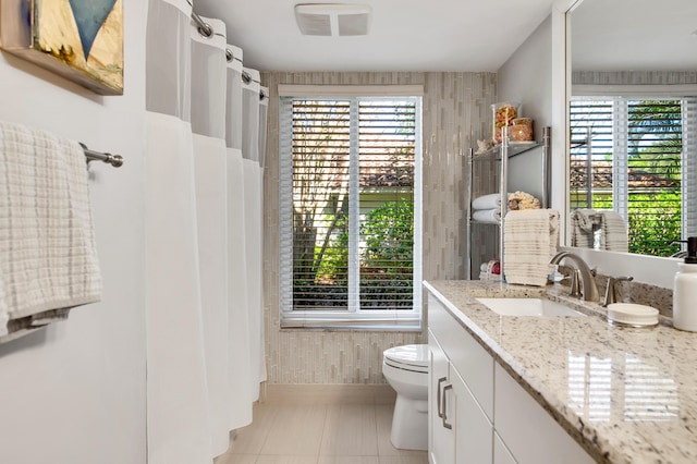 bathroom featuring a wealth of natural light, tile patterned flooring, vanity, and toilet