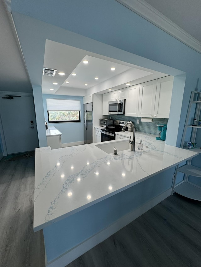 kitchen with backsplash, kitchen peninsula, dark hardwood / wood-style flooring, white cabinetry, and stainless steel appliances