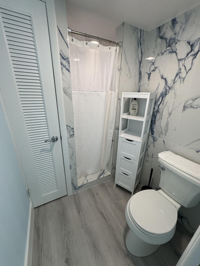 bathroom featuring a shower with shower curtain, toilet, tile walls, and hardwood / wood-style flooring