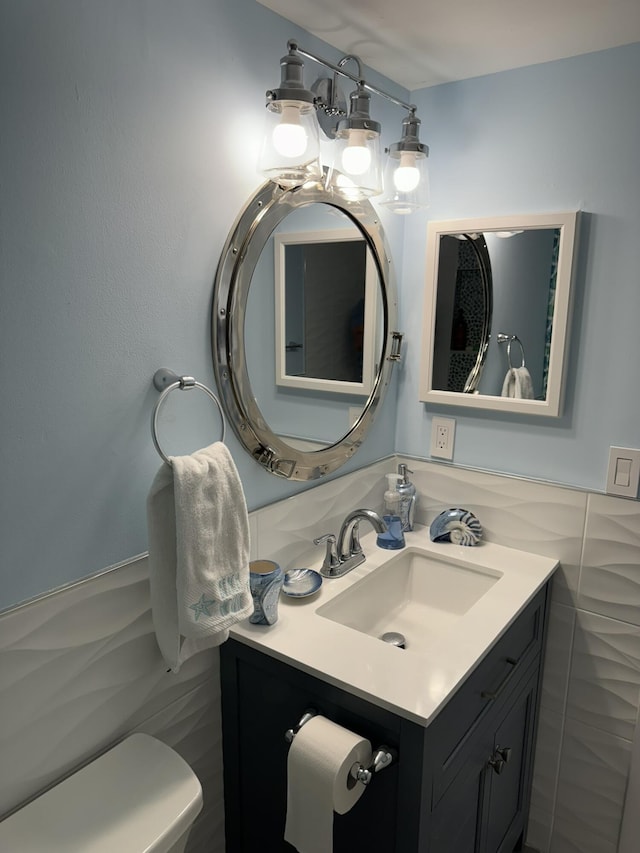 bathroom with vanity, toilet, and tile walls