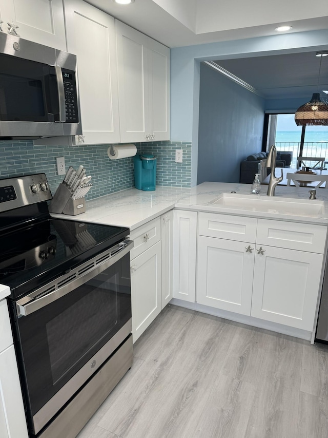 kitchen with white cabinets, stainless steel appliances, light hardwood / wood-style floors, and sink