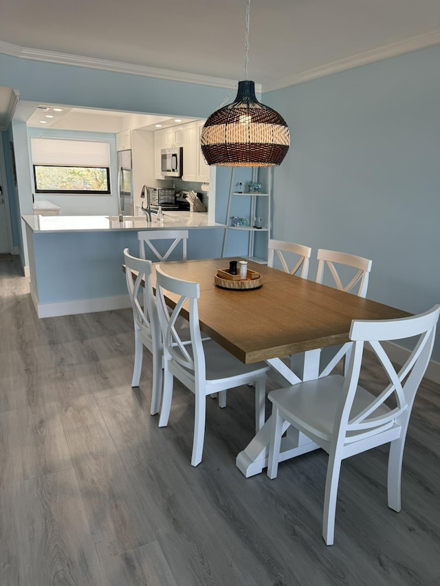 dining room with hardwood / wood-style flooring, sink, and crown molding