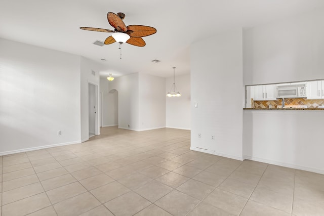 unfurnished living room featuring ceiling fan with notable chandelier and light tile patterned flooring