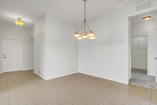 tiled empty room with a notable chandelier