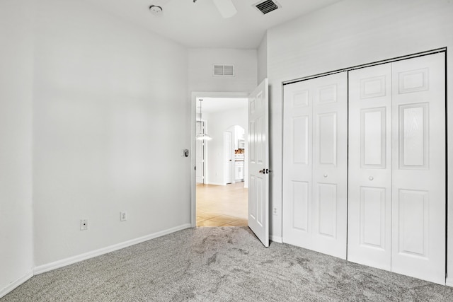 unfurnished bedroom featuring light carpet, a closet, and ceiling fan