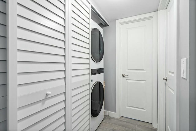 clothes washing area with hardwood / wood-style floors and stacked washer / dryer