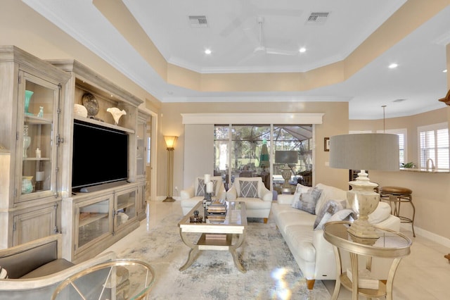 tiled living room with a tray ceiling, crown molding, and ceiling fan