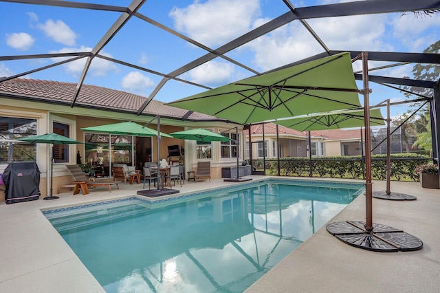 view of pool featuring glass enclosure, area for grilling, and a patio