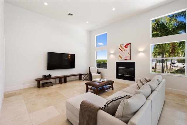 living room with a healthy amount of sunlight, light tile patterned floors, and a high ceiling