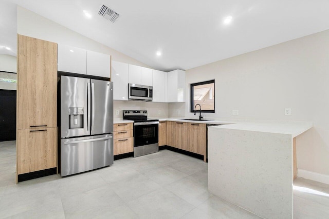 kitchen featuring white cabinets, appliances with stainless steel finishes, lofted ceiling, and sink