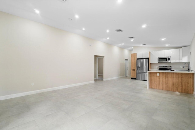 kitchen with white cabinets, lofted ceiling, sink, and appliances with stainless steel finishes