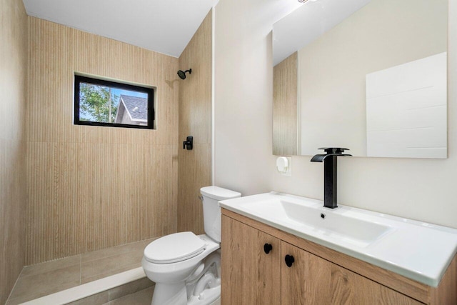 bathroom featuring a tile shower, tile patterned floors, vanity, and toilet