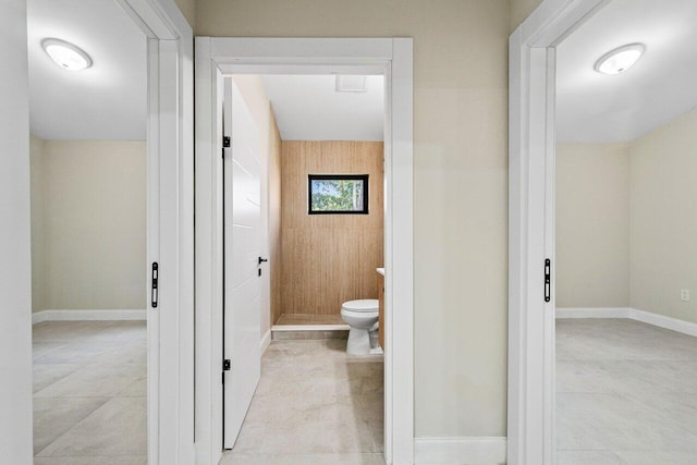 bathroom featuring toilet and wood walls