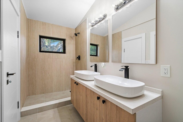 bathroom featuring tile patterned flooring, vanity, a tile shower, and vaulted ceiling