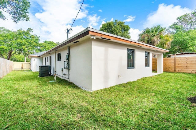 rear view of house featuring cooling unit and a lawn