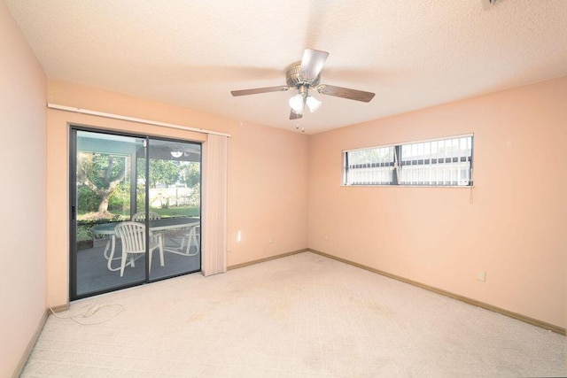 empty room featuring a wealth of natural light, ceiling fan, and light carpet