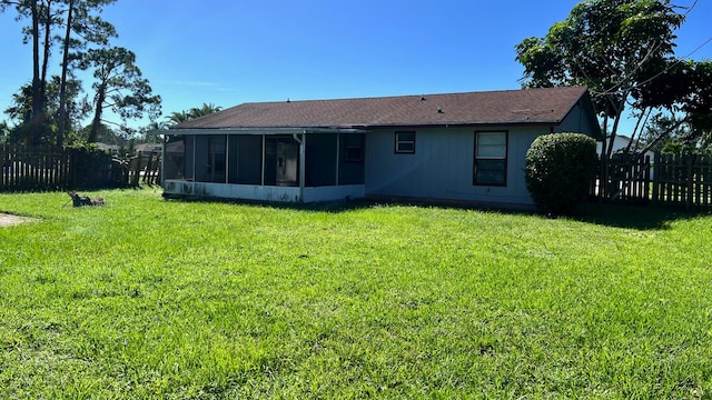 rear view of property featuring a sunroom and a lawn