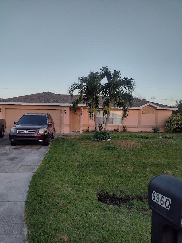 ranch-style house featuring a garage and a front lawn