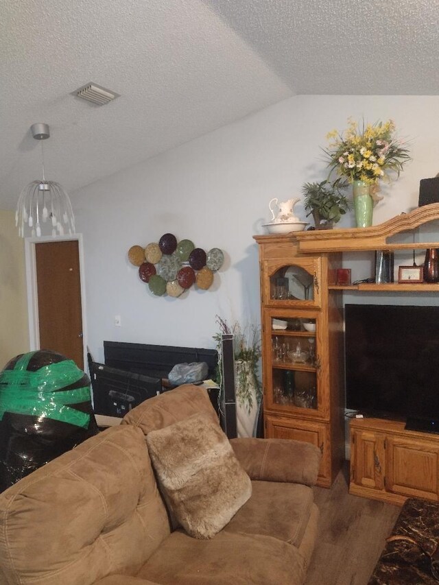 living room with hardwood / wood-style floors, lofted ceiling, and a textured ceiling