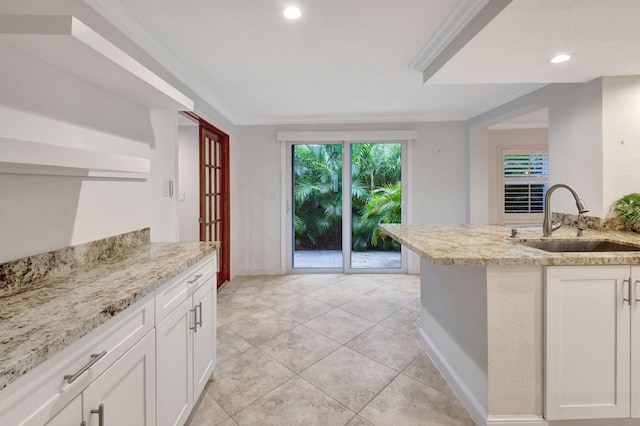 kitchen featuring light stone countertops, sink, white cabinetry, and ornamental molding