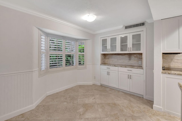 kitchen with tasteful backsplash, crown molding, white cabinetry, a textured ceiling, and light stone counters