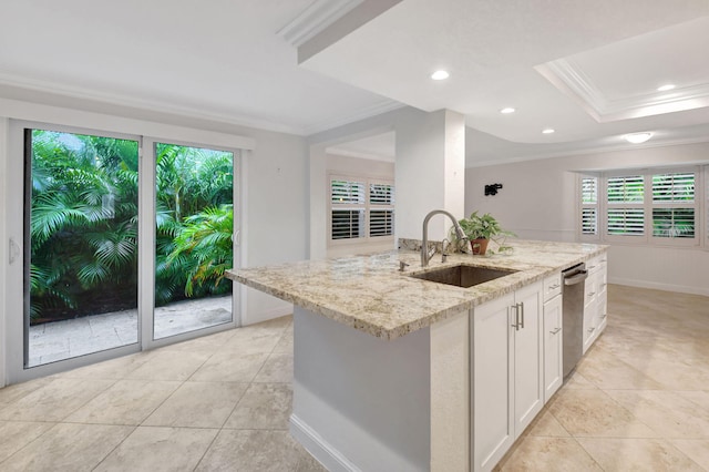 kitchen featuring light stone countertops, white cabinetry, sink, a center island with sink, and crown molding