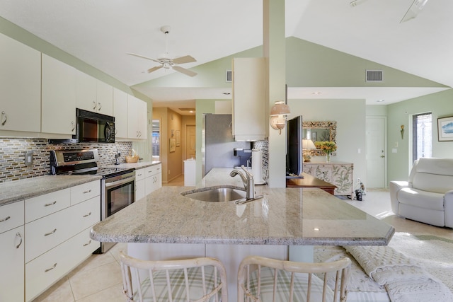 kitchen featuring a kitchen breakfast bar, sink, appliances with stainless steel finishes, and vaulted ceiling