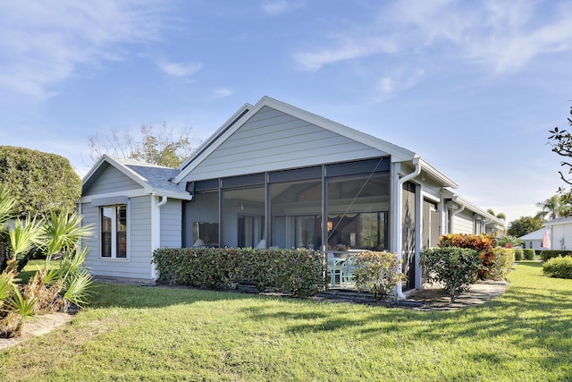 back of property with a lawn and a sunroom