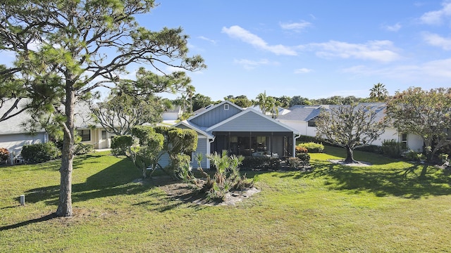 rear view of house featuring a sunroom and a lawn