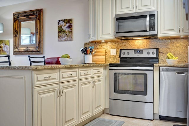 kitchen with light stone counters, light tile patterned floors, appliances with stainless steel finishes, and tasteful backsplash