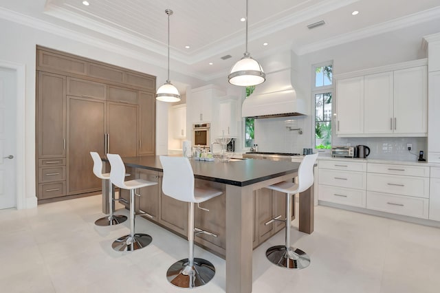 kitchen with stainless steel oven, white cabinets, a kitchen breakfast bar, a spacious island, and tasteful backsplash