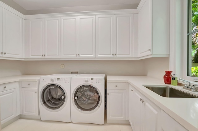 clothes washing area with cabinets, washing machine and dryer, light tile patterned flooring, and sink