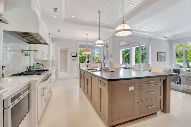 kitchen with plenty of natural light, custom exhaust hood, decorative light fixtures, and sink