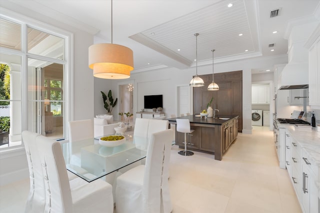 dining area with a tray ceiling, ornamental molding, and washing machine and clothes dryer