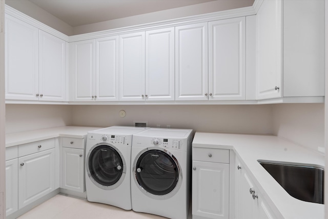 laundry room with sink, washing machine and dryer, and cabinets