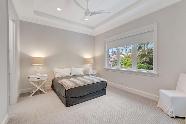 carpeted bedroom featuring ornamental molding, ceiling fan, and a tray ceiling