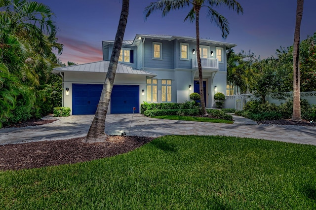 view of front of home featuring a garage, a balcony, and a yard